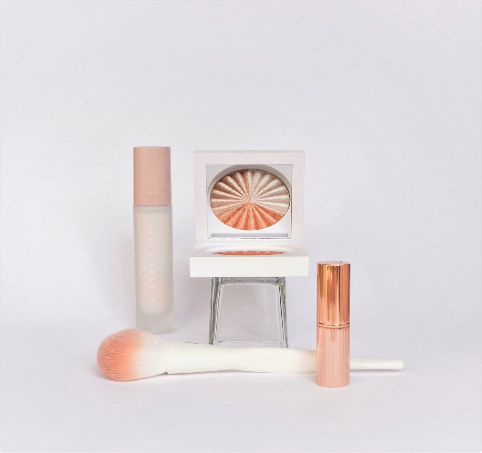 A minimalist composition of luxurious makeup items on a white background.